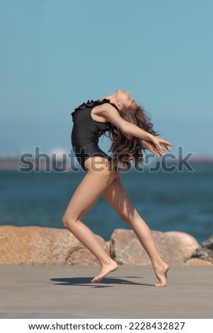 young graceful and flexible gymnast in swimsuit flexibility by the sea
