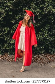 A Young Graduate Posing In Her Red Cap And Gown