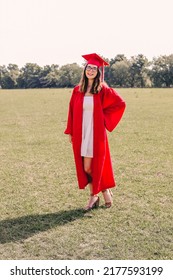 A Young Graduate Posing In Her Red Cap And Gown