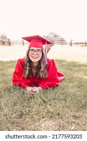 A Young Graduate Posing In Her Red Cap And Gown