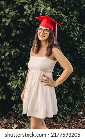 A Young Graduate Posing In Her Red Cap And Gown