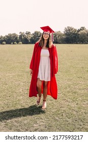 A Young Graduate Posing In Her Red Cap And Gown