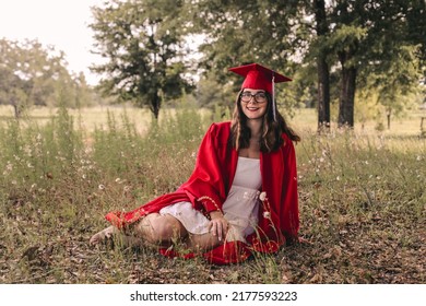 A Young Graduate Posing In Her Red Cap And Gown