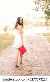 A Young Graduate Posing In Her Red Cap And Gown