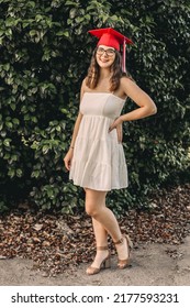 A Young Graduate Posing In Her Red Cap And Gown