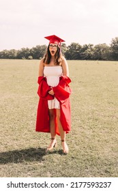 A Young Graduate Posing In Her Red Cap And Gown