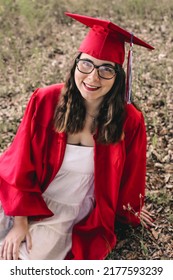 A Young Graduate Posing In Her Red Cap And Gown