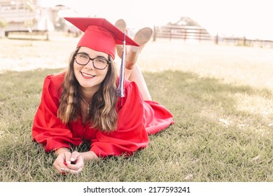 A Young Graduate Posing In Her Red Cap And Gown