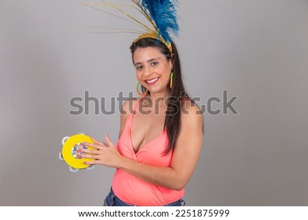 young graduate woman on gray background dressed for carnival night playing a tambourine