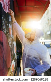 Young Graffiti Artist Painting Mural Outdoors On Street Wall.