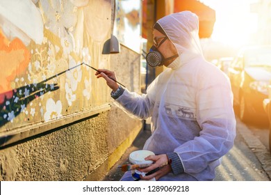 Young Graffiti Artist Painting Mural Outdoors On Street Wall.