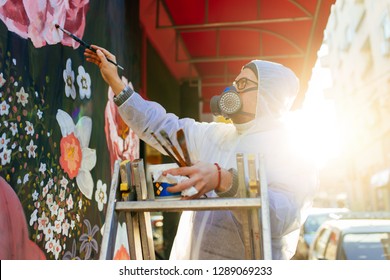 Young Graffiti Artist Painting Mural Outdoors On Street Wall.