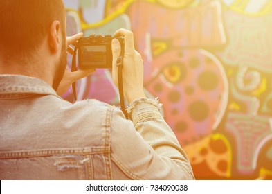 A Young Graffiti Artist Photographs His Completed Picture On The Wall. The Guy Uses Modern Technology To Capture A Colorful Abstract Graffiti Drawing. Focus On The Photographing Device