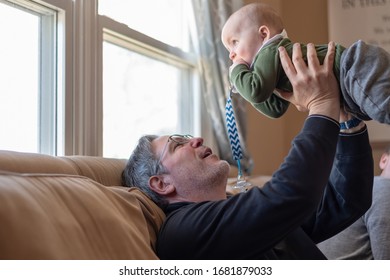 Young Grandfather Lifting Baby Grandson In The Air