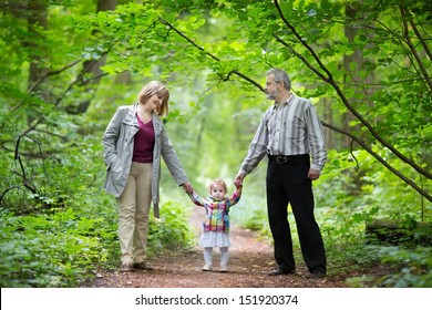 Young Grandparents Walking With Their Baby Granddaughter In A Park In Autumn