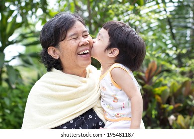 Young Grandson Giving His Grandma A Big Smooch On The Cheek,Asian People