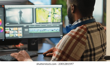 Young graphic designer artist editing video content on software, using focus lighting and color grading. Male filmmaker working on movie montage edit on pc multi monitors, cinematographer.