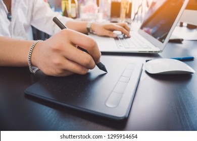 Young graphic designer man using tablet and computer laptop on black table at home office