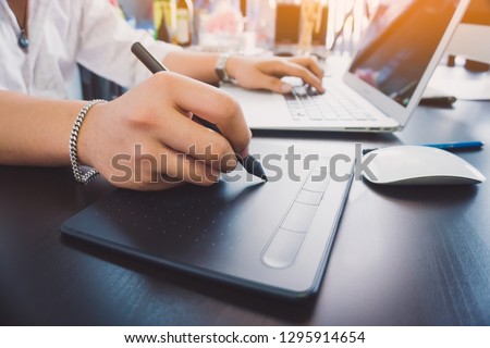 Young graphic designer man using tablet and computer laptop on black table at home office