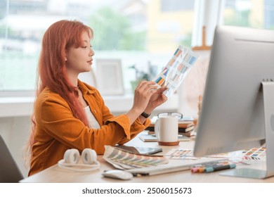 Young graphic designer with red hair examining a color swatch in a creative office. - Powered by Shutterstock