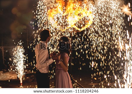Young groom and bride with two burning hearts fireshow at night, wedding or marriage concept