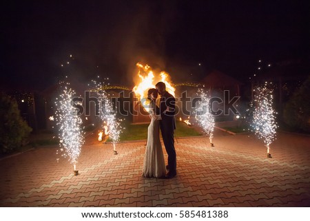 Young groom and bride with two burning hearts fireshow at night, wedding or marriage concept.