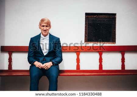 Young groom on red vintage rural bench
