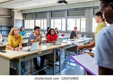 Young group of diverse high school students giving a presentation to classmate friends in classroom - Male and female college student attending to classmates lecture - Diversity and education concept - Powered by Shutterstock