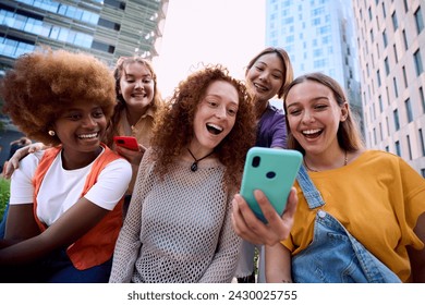 Young group of gen z people having fun surprised using cell phone together outside watching something funny at mobile. Cheerful community of student enjoying social media content. Multiethnic friends - Powered by Shutterstock