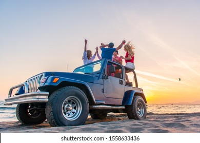 Young Group Having Fun On The Beach Drink Beer And Dancing In A Convertible Car