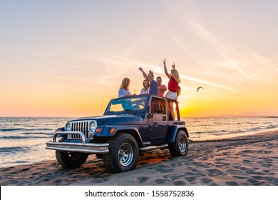 Young group having fun on the beach drink beer and dancing in a convertible car