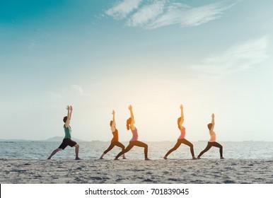 Young group man and woman yoga practice on mat relaxation in class exercise with pose fitness sport for healthy on the beach and seaside  modern city at sunrise relax