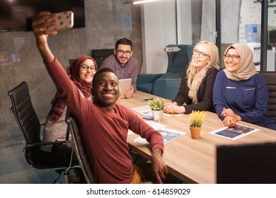 Young group of multiethnic business people on a meeting in meeting room taking selfie before meeting