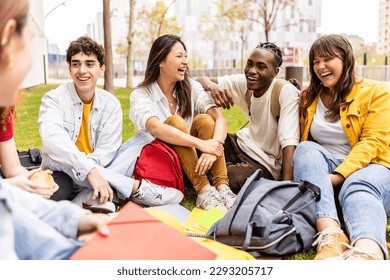 Young group of multiracial students laughing and having fun together sitting on the grass in the university campus. Teenage classmates social gathering relaxing outdoors. - Powered by Shutterstock