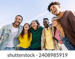 Young group of people having fun together outdoors in a sunny day. Multiracial best friends bonding enjoying time together at city street. United millennial students laughing.