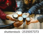 Young group of people having fun cheering with beer outdoor at pub restaurant - Winter lifestyle and party concept - Soft focus on right glass