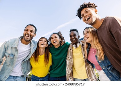 Young group of people having fun together outdoors in a sunny day. Multiracial best friends bonding enjoying time together at city street. United millennial students laughing.