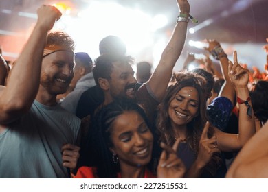 A young group of people are partying and dancing at the concert with smiles on their faces and fashionable clothes. - Powered by Shutterstock