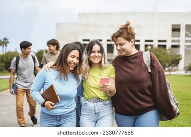 Young group of students having fun outdoor using smartphone while going out from university building - Back to school concept - Focus on center girl face - Shutterstock ID 2330777665