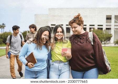 Young group of students having fun outdoor using smartphone while going out from university building - Back to school concept - Focus on center girl face