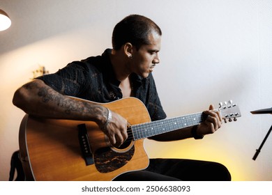 Young guitarist playing acoustic guitar in musical studio	 - Powered by Shutterstock