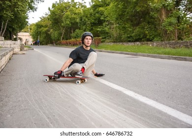 A young guy action makes a slide on a longboard in the resort area of the city