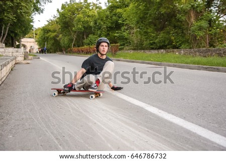A young guy action makes a slide on a longboard in the resort area of the city