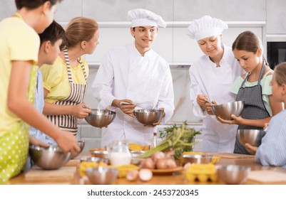 ..Young guy and adult woman chef at master class teaches group of children how to cook food - Powered by Shutterstock