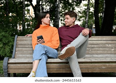 A young guy approaches a woman on a park bench. A young woman is not happy to meet her and looks coldly at a young man - Powered by Shutterstock