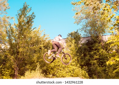 a young guy, an athlete, performs tricks with a bike, jumps on the springboard. in the forest. against the setting sun - Powered by Shutterstock