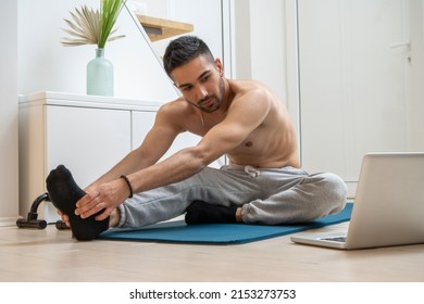 Young guy with average body type trying to improve his muscles, lose belly fat and lose weight on specific body parts while watching online workout courses and practicing on exercise mat at home.