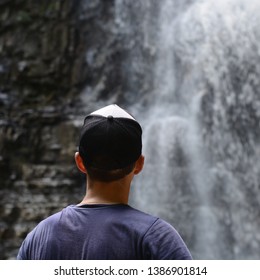Young guy from the back on the background of rocks and a waterfall