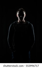 Young Guy Is Backlit Against A Black Background