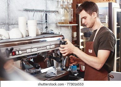 A young guy Barista works at the coffee shop.